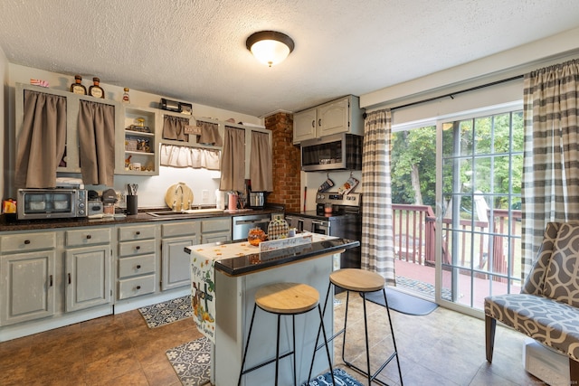 kitchen with gray cabinets, stainless steel appliances, a textured ceiling, a center island, and sink