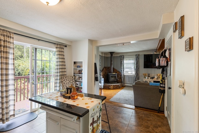 kitchen with a textured ceiling, plenty of natural light, a wood stove, and white cabinetry