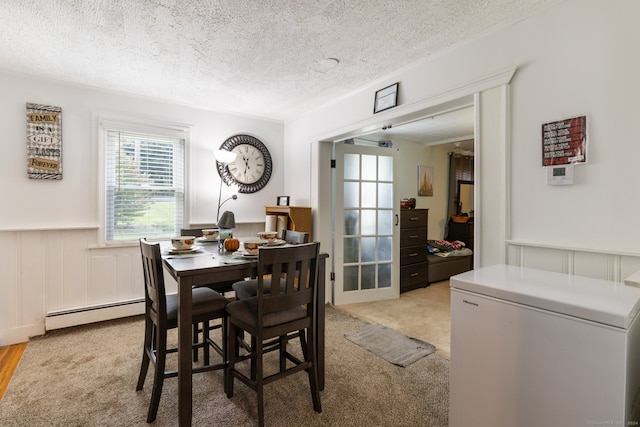 dining area featuring light colored carpet, a textured ceiling, and baseboard heating