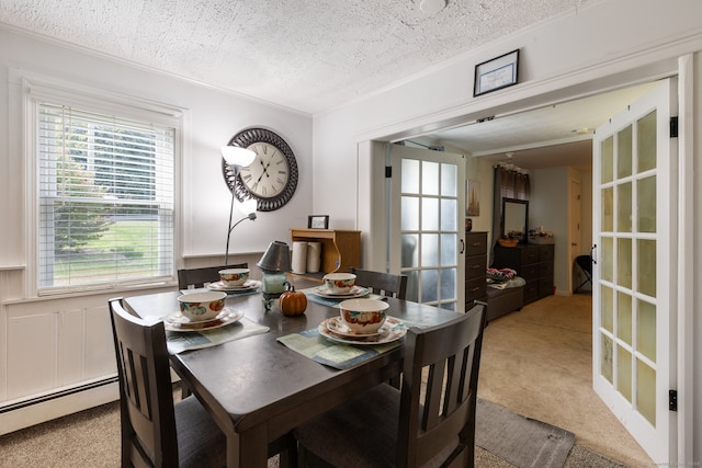 dining space with a textured ceiling, light colored carpet, and a baseboard radiator