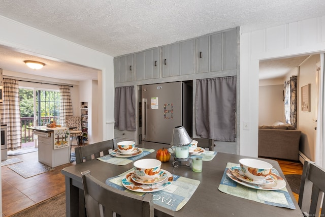 dining space featuring a textured ceiling, tile patterned flooring, and a baseboard radiator