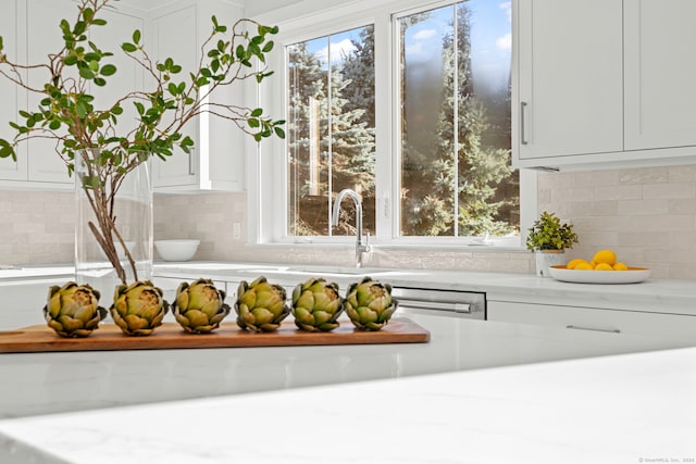 details with tasteful backsplash, dishwasher, sink, and white cabinets