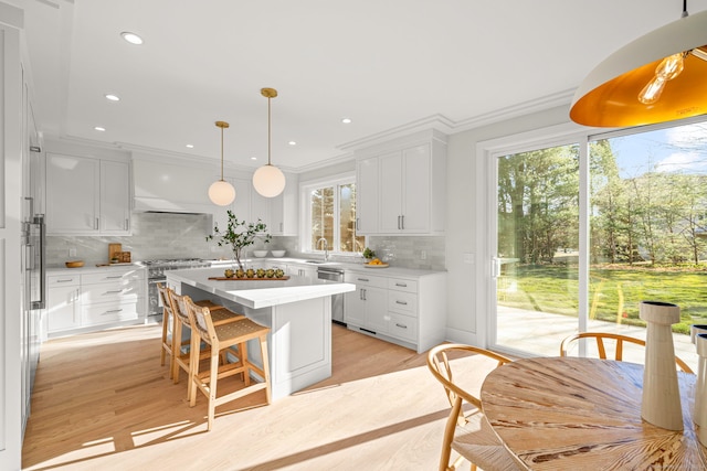 kitchen featuring a center island, appliances with stainless steel finishes, tasteful backsplash, light hardwood / wood-style floors, and white cabinetry