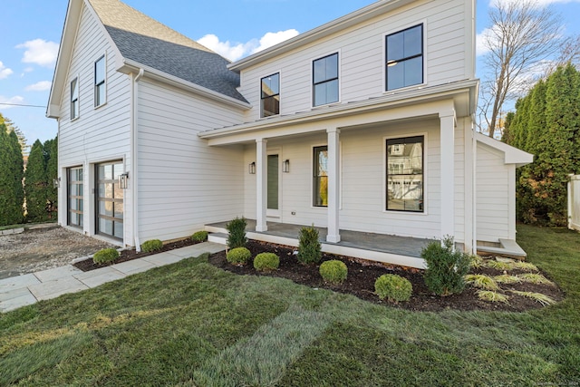 view of front of home with covered porch, a garage, and a front yard