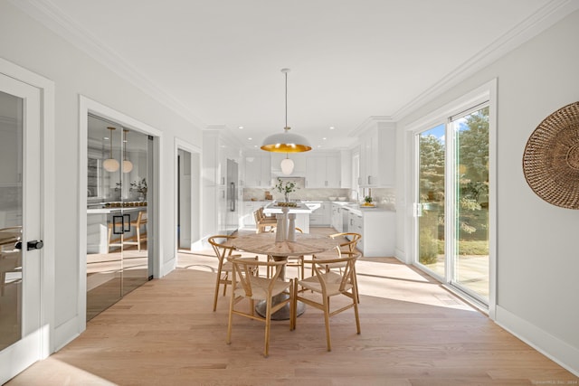 dining space with crown molding and light hardwood / wood-style flooring