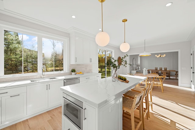 kitchen with white cabinetry, sink, stainless steel appliances, light hardwood / wood-style flooring, and a kitchen island