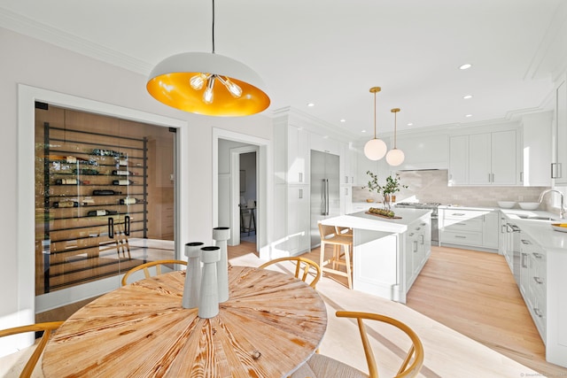 dining area featuring light wood-type flooring, ornamental molding, and sink