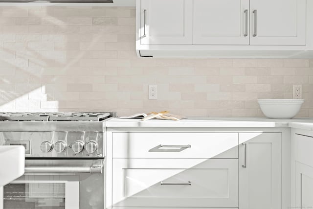 room details featuring tasteful backsplash, white cabinetry, and stainless steel range