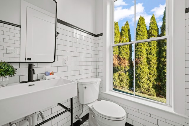 bathroom featuring toilet, sink, and tile walls