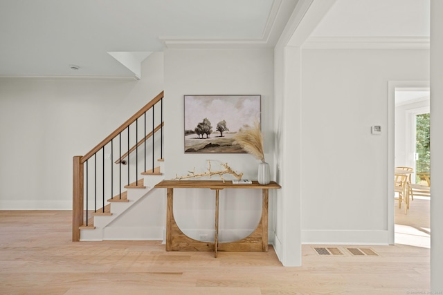 stairs with wood-type flooring and crown molding