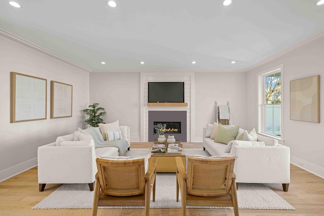 living room with a fireplace, ornamental molding, and light wood-type flooring