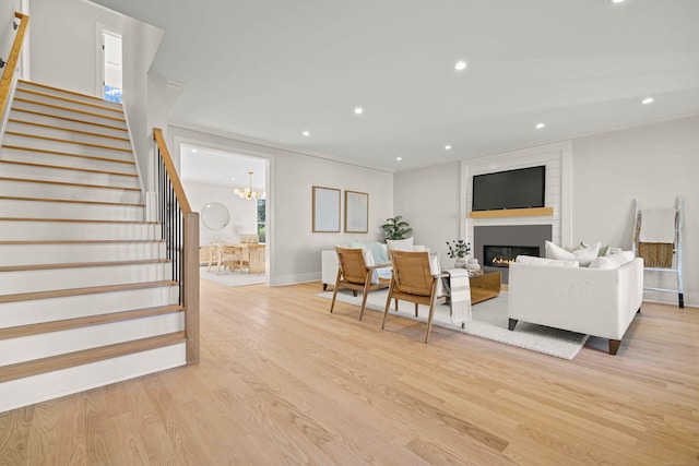 living room featuring a fireplace, light hardwood / wood-style floors, and crown molding