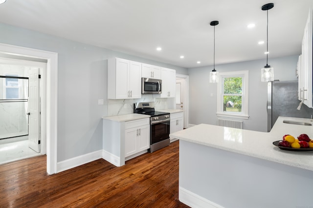 kitchen featuring white cabinets, appliances with stainless steel finishes, hanging light fixtures, and dark wood-type flooring