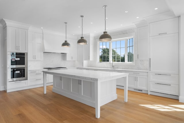 kitchen with pendant lighting, white cabinets, light hardwood / wood-style floors, and stainless steel double oven