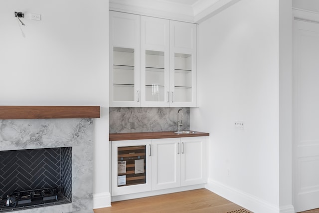 bar featuring butcher block countertops, white cabinetry, light hardwood / wood-style flooring, and wine cooler