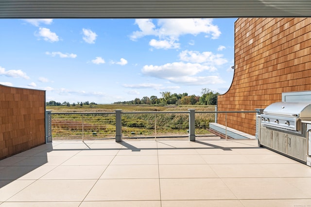 view of patio with grilling area, a rural view, and an outdoor kitchen