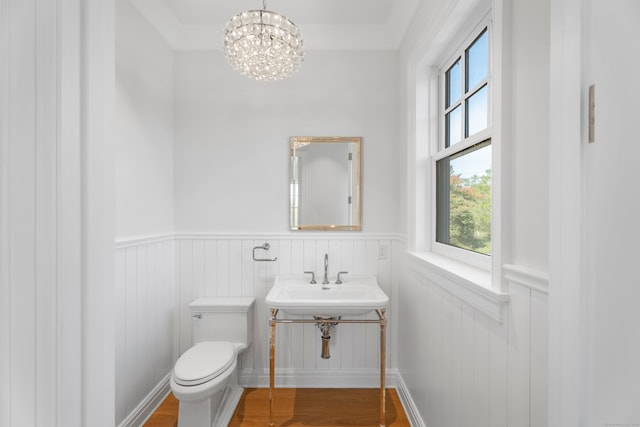 bathroom featuring ornamental molding, sink, wood-type flooring, a chandelier, and toilet