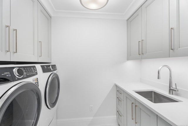 clothes washing area featuring washer and clothes dryer, cabinets, crown molding, and sink