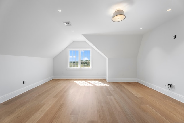 bonus room with light wood-type flooring and vaulted ceiling