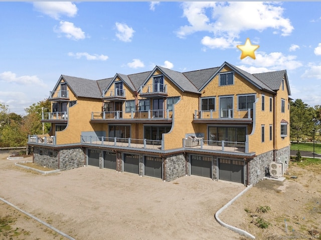 back of property with a balcony, ac unit, and a garage