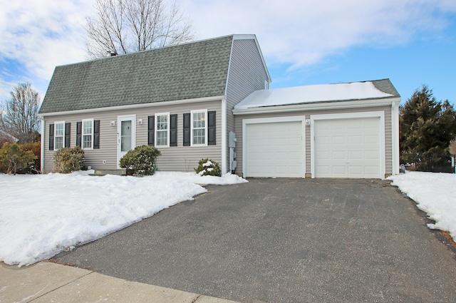 colonial inspired home with a shingled roof, an attached garage, a gambrel roof, and aphalt driveway