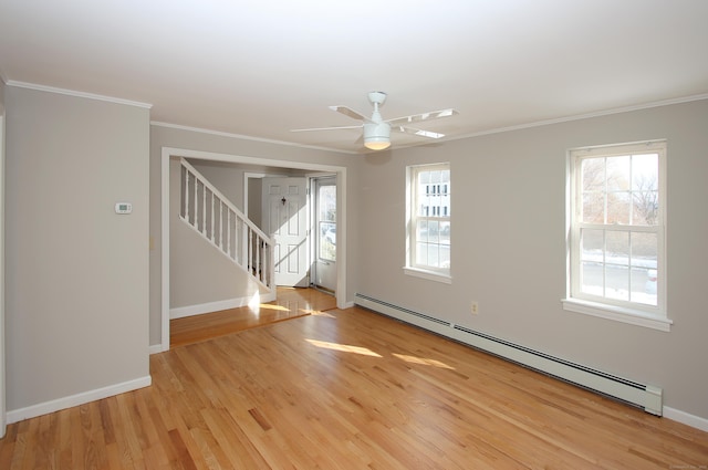 spare room featuring light wood-style flooring, a baseboard heating unit, baseboards, stairway, and crown molding