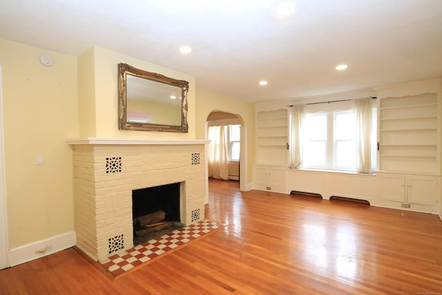 25 Muriel St, Norwalk, CT 06851 - unfurnished living room featuring a brick fireplace, arched walkways, recessed lighting, baseboards, and wood finished floors