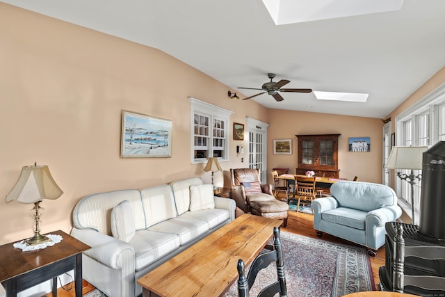 living room with wood-type flooring, lofted ceiling with skylight, and ceiling fan