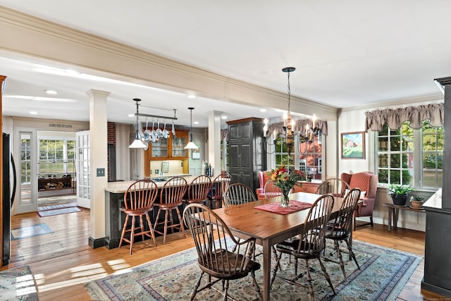 dining room featuring light hardwood / wood-style floors, crown molding, and ornate columns