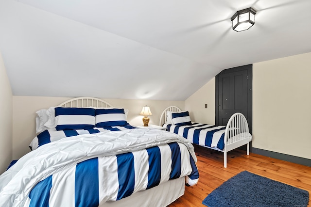 bedroom featuring hardwood / wood-style flooring and lofted ceiling