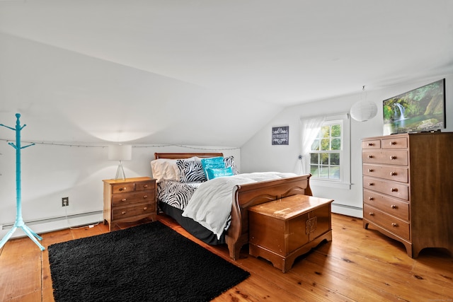 bedroom featuring a baseboard heating unit, lofted ceiling, and light wood-type flooring