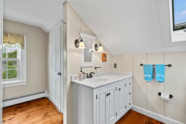 bathroom featuring lofted ceiling with skylight, vanity, a baseboard heating unit, and hardwood / wood-style flooring