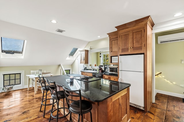 kitchen with dark hardwood / wood-style flooring, lofted ceiling with skylight, white appliances, and a wall mounted AC