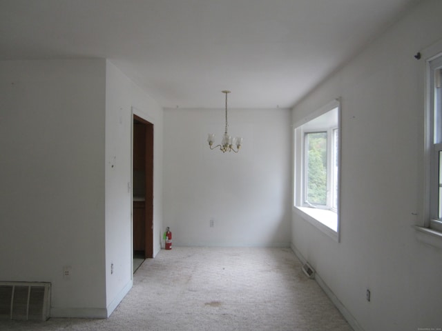 unfurnished dining area with a chandelier and light colored carpet