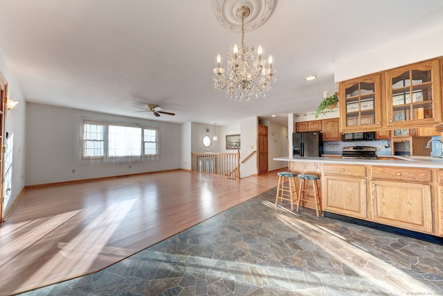 kitchen featuring hardwood / wood-style flooring, a kitchen breakfast bar, hanging light fixtures, backsplash, and black appliances