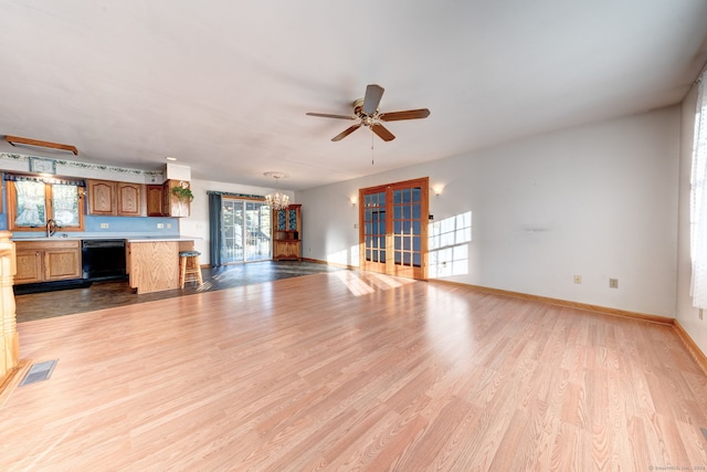 unfurnished living room with light hardwood / wood-style flooring, sink, and ceiling fan with notable chandelier