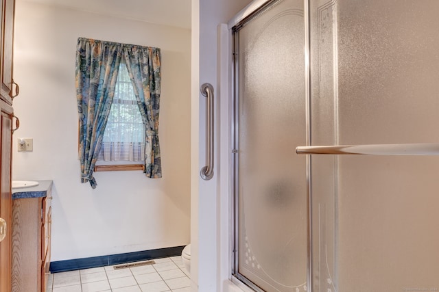 bathroom featuring vanity, a shower with shower door, toilet, and tile patterned floors