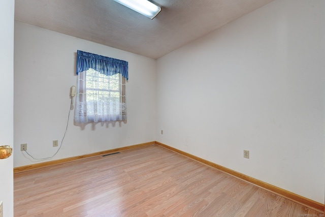 unfurnished room with vaulted ceiling and light wood-type flooring