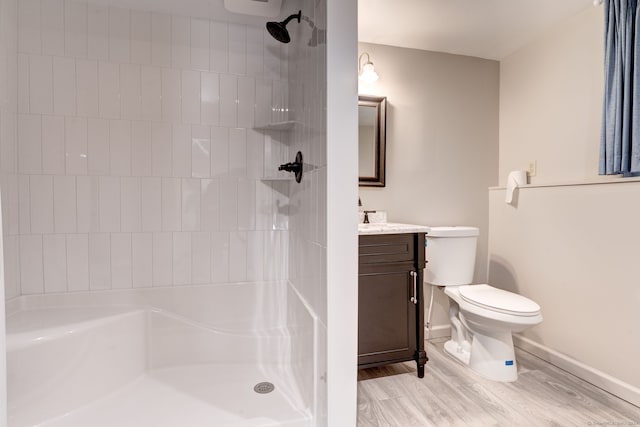 bathroom with vanity, toilet, wood-type flooring, and tiled shower