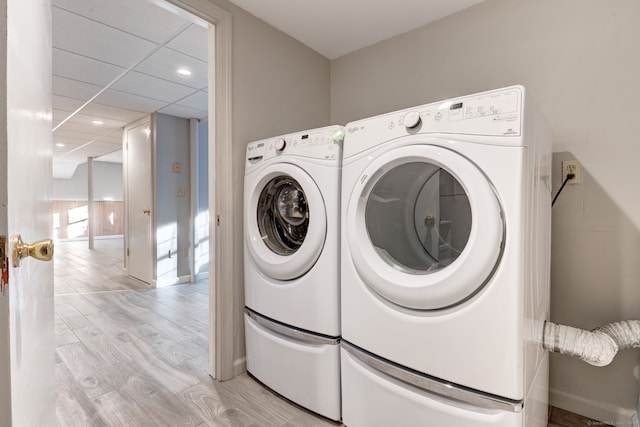 clothes washing area with light wood-type flooring and washing machine and clothes dryer