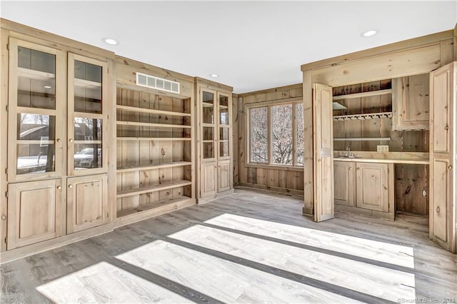 interior space with light hardwood / wood-style flooring and wood walls