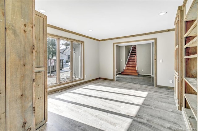 spare room featuring light wood-type flooring and ornamental molding