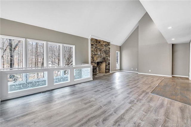 unfurnished living room with high vaulted ceiling, light hardwood / wood-style floors, and a fireplace