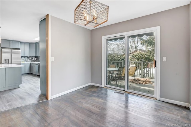 unfurnished dining area featuring an inviting chandelier and dark hardwood / wood-style floors