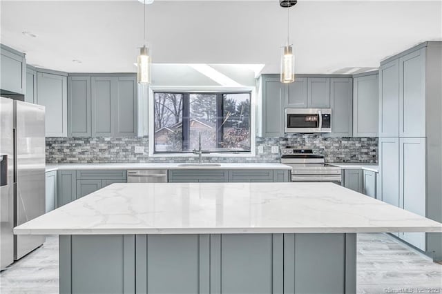 kitchen with light stone counters, stainless steel appliances, sink, and a kitchen island