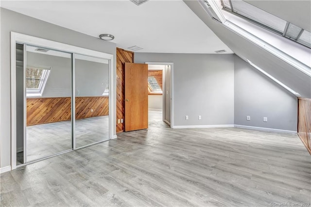 interior space featuring a closet, wood walls, and light hardwood / wood-style floors