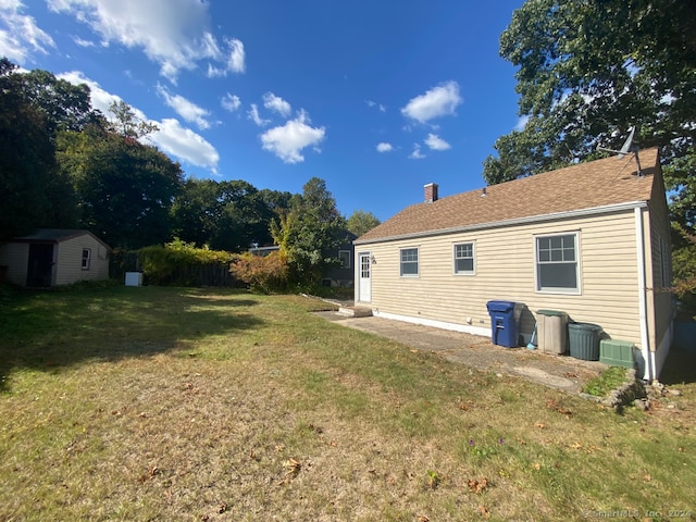 rear view of house featuring a lawn and a shed