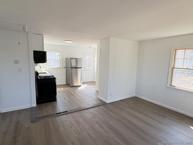 unfurnished room with a sink, baseboards, visible vents, and wood finished floors