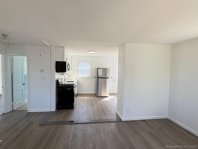 kitchen with appliances with stainless steel finishes, white cabinets, and wood finished floors