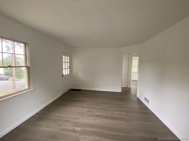 unfurnished room with wood finished floors, visible vents, and baseboards